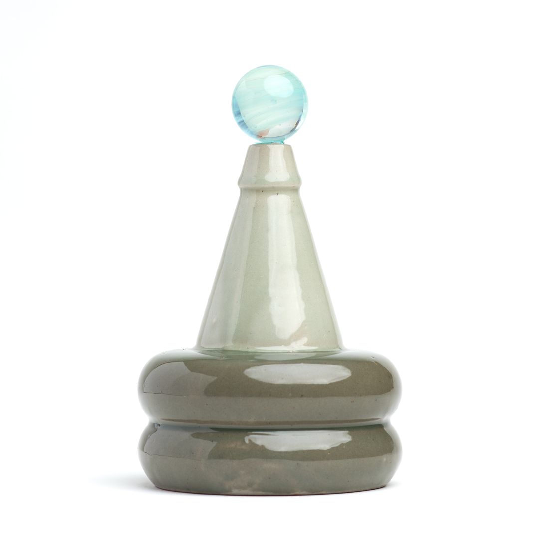 Apian Cuir ceramic vessel on white, a stacked glazed form holding a glass orb.