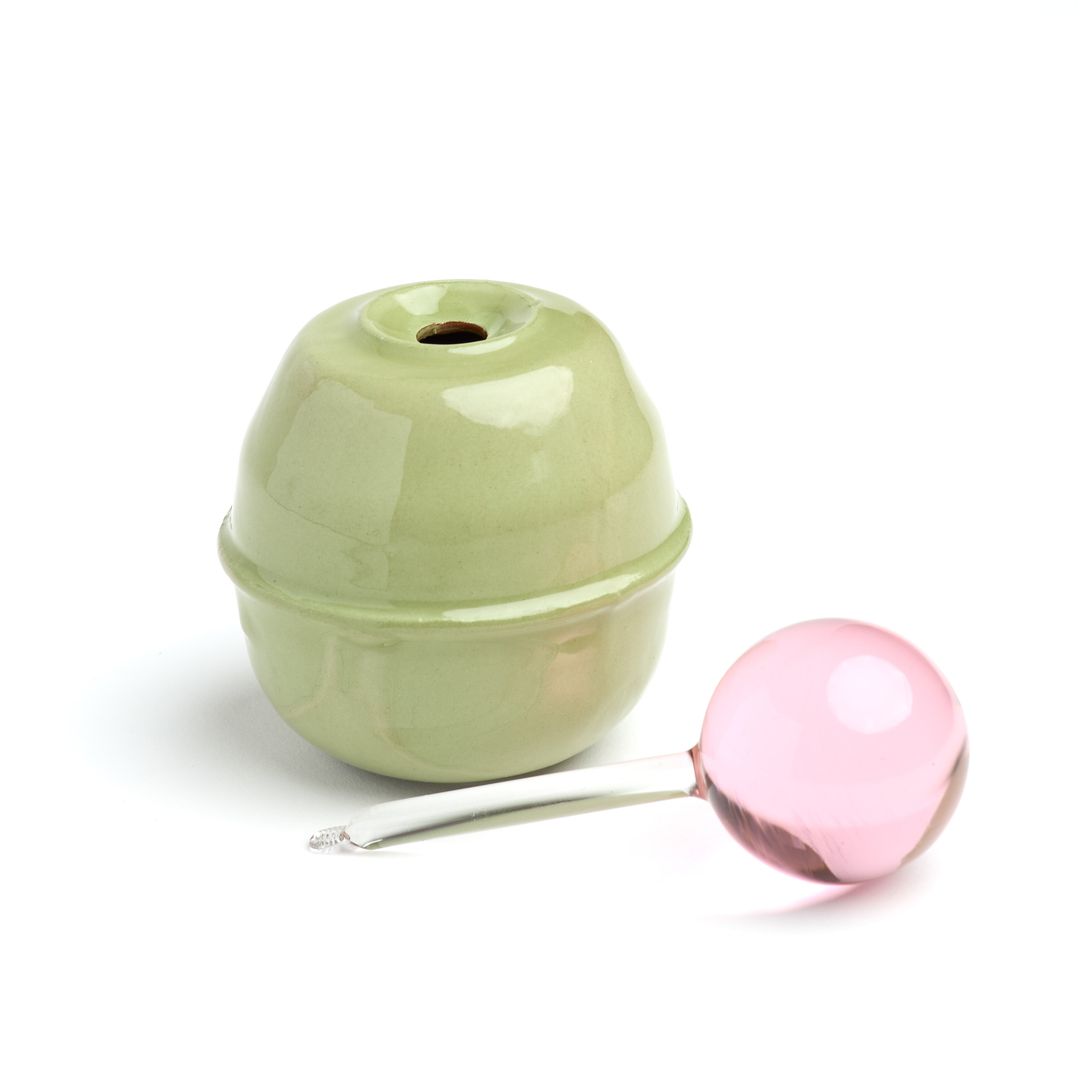 The open Rose Interval ceramic base beside its borosilicate glass applicator, on white.
